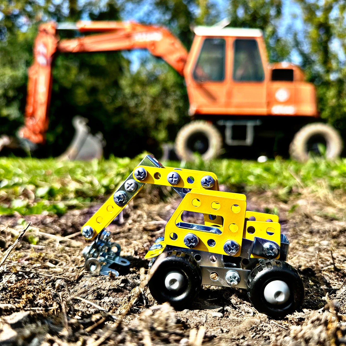 kleiner Bagger neben echtem Bagger auf der Baustelle
